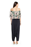 Front view of white abutilon print off-shoulder ruffle top and black art crepe low crotch pant with tassels